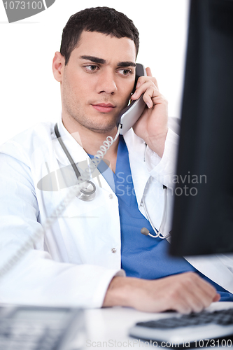 Image of Portrait of male physician holding receiver and looking the computer