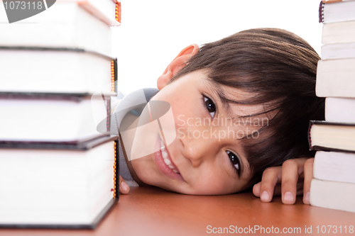 Image of Happy young school boy surrounded by books