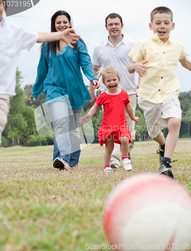 Image of Sportive family playing football on the green lawn