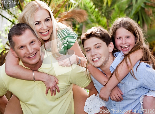 Image of Loving father and son gives piggyback to their wife and daughter