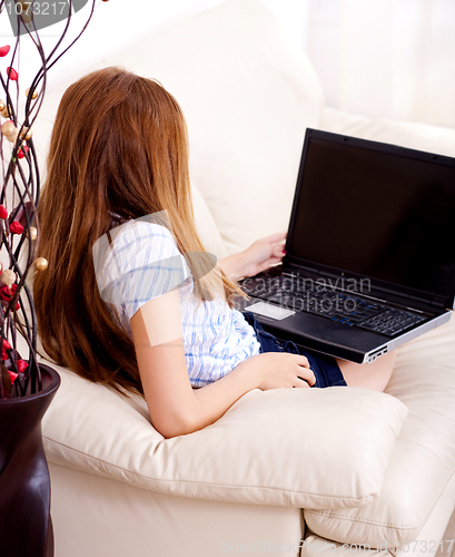 Image of Beautiful young brunette using a laptop at home