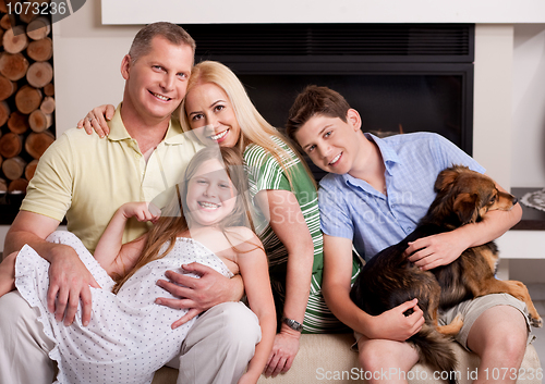 Image of Happy domestic family sitting in living room with dog