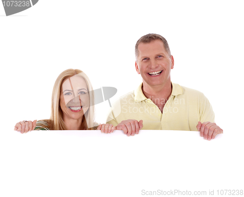 Image of Middle aged couple standing behind a blank white board and smiling