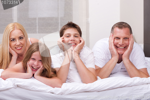 Image of Beautiful family lying on bed smiling and looking at you