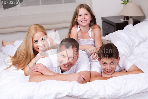 Image of Happy family having fun on the bed