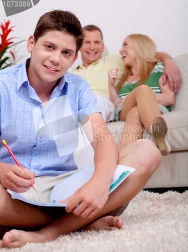 Image of Young smiling teenager sitting with his book in living room