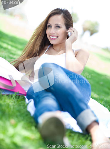 Image of Young women lying in park using mobile phone