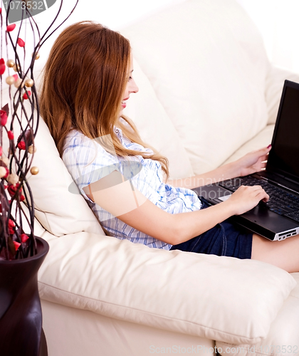 Image of Beautiful young brunette using a laptop at home
