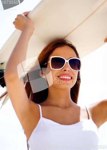 Image of Smiling beach woman holding surfboard on her head