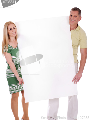 Image of Middle aged smiling couple holding a blank white board