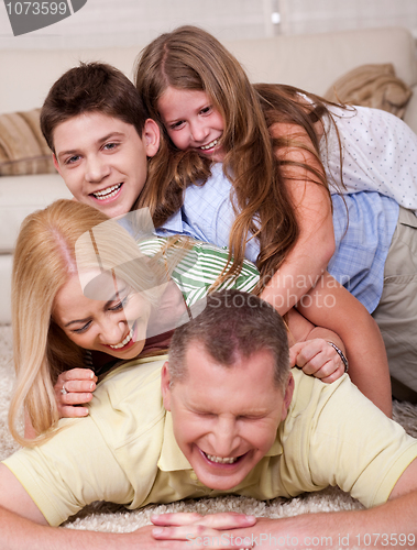 Image of Happy family of four having fun in bed