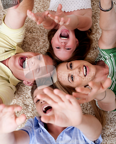 Image of Happy family of four lying on the carpet