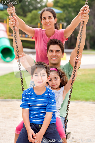 Image of Jolly caucasian family swinging in the park