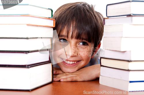 Image of Young kid relaxing between pile of books