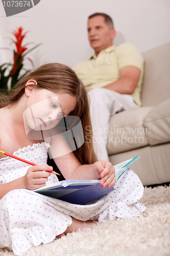 Image of Cute girl studying with her father in the background