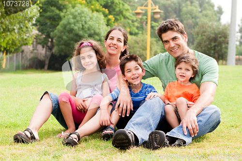 Image of Family seated in park and smiling at camera