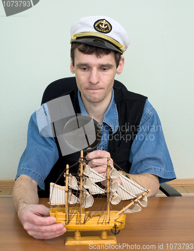 Image of Guy in a sea cap with toy sailing vessel