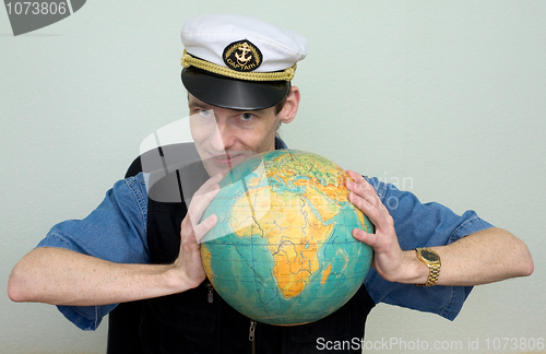 Image of Man in a sea cap compresses globe in hands