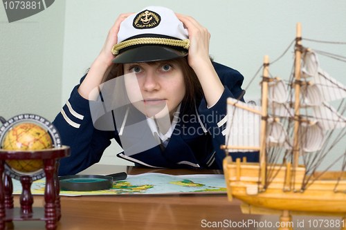 Image of Scared girl in sea uniform at a table