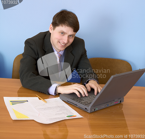 Image of Businessman sits at table with the laptop