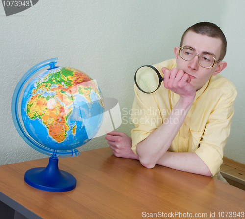 Image of Young man with a magnifier and globe
