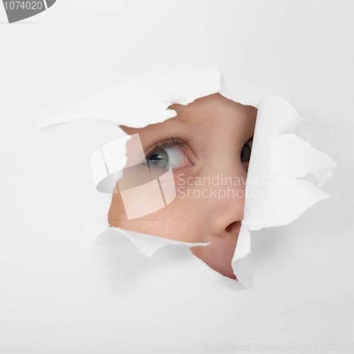 Image of Childish eye looking from hole in paper