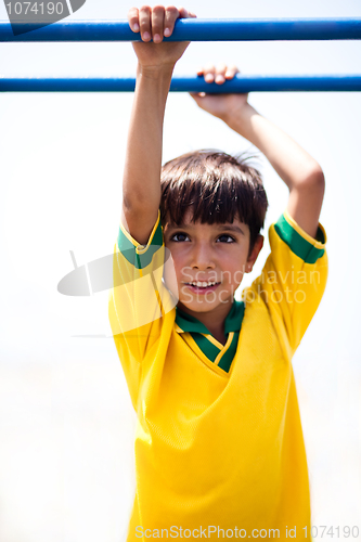 Image of Young boy hanging on jungle gym