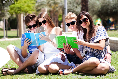 Image of Young couples relaxing in park and reading books