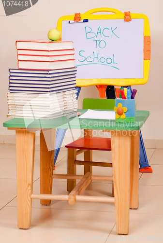 Image of School books and apple on desk with sketchboard