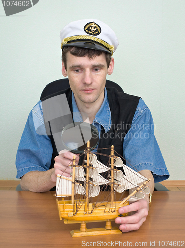 Image of Man with a magnifier and model of a sailing vessel
