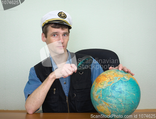 Image of Guy in a sea uniform cap with globe and magnifier