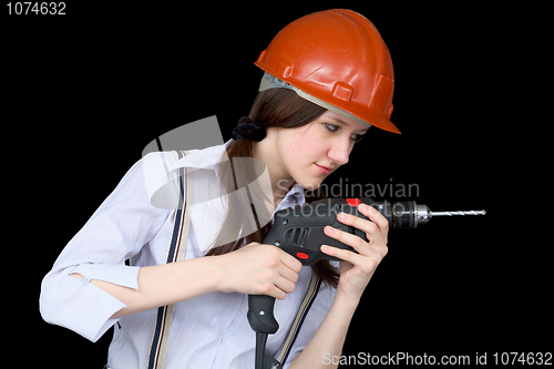 Image of Young woman in a protective helmet with a drill