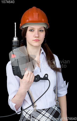 Image of Beautiful girl in a protective helmet with a drill