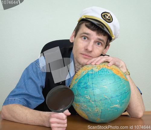 Image of Man in a sea uniform cap with globe and magnifier