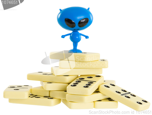 Image of Blue toy alien on a heap from dominoes