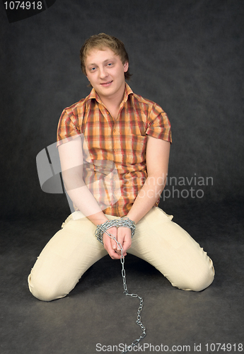 Image of Man chained in a chain is kneeling