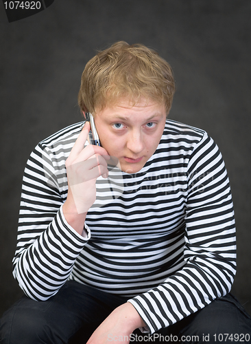 Image of Seaman in a stripped vest with a mobile phone