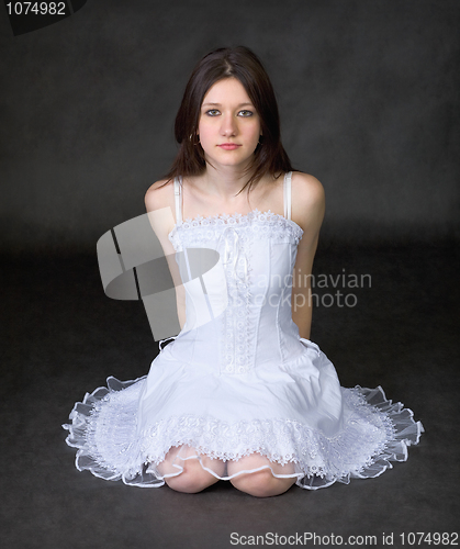 Image of Girl in a white dress sits on a black background