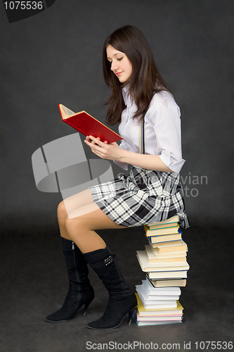 Image of Girl reads the book, sitting on pile of books