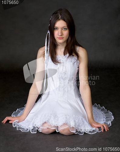 Image of Girl in white dress sits on a black