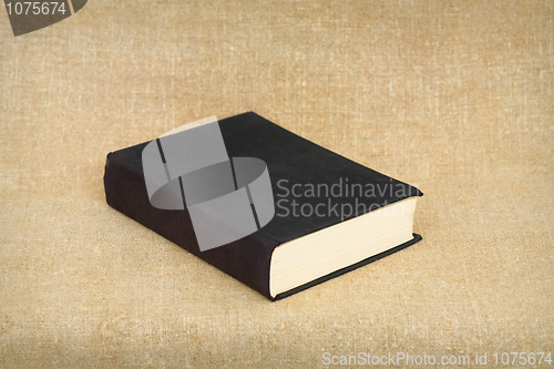 Image of Old big black book on brown canvas background