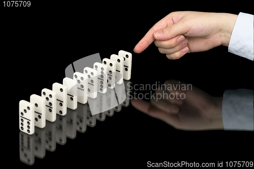 Image of Hand pushing dominoes counters on black