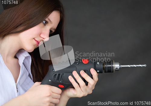 Image of Young beautiful girl with drill in hands