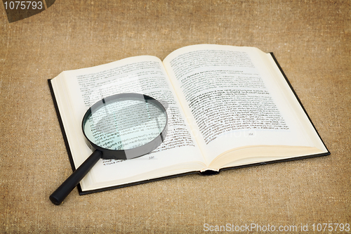 Image of Open book and magnifier against a canvas - a still-life