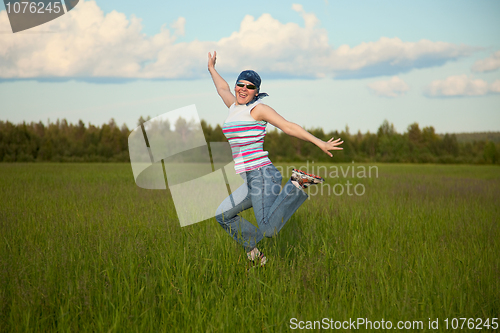 Image of Girl in bandana jumping on a green field