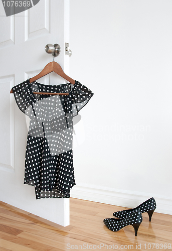 Image of Polka dot blouse on a hanger and shoes on the floor