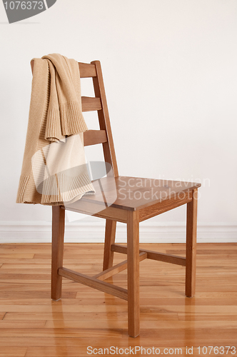 Image of Chair on wooden floor with clothing put over its back