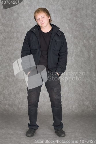 Image of Young guy in a jacket standing on a grey background