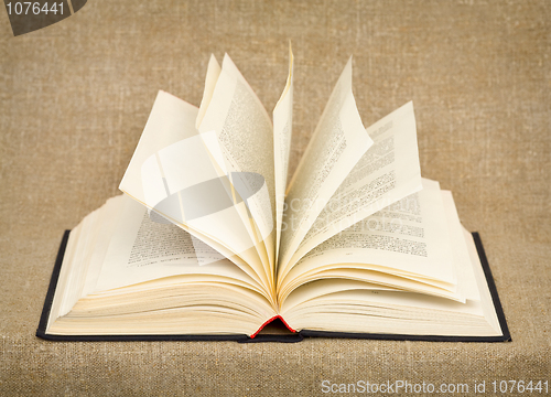 Image of Big open old book lying against a rough canvas