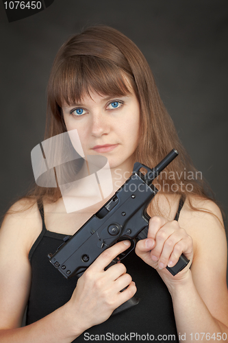 Image of Serious beauty armed with submachine gun on a black